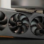 Triple‑fan graphics card from Gigabyte installed in a PC, visible heatsink and case side panel in the background, slogan 'Dominating the Games' on the card.